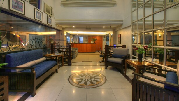 Um lobby amplo com balcão de recepção, áreas de estar e um padrão decorativo no chão.