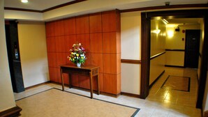 Um lobby com uma recepção de madeira e um vaso de flores.
