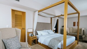A four-poster bed with a wooden frame, a beige armchair with a patterned pillow, a bedside table with a lamp, and a wooden door. - Matsumoto Marunouchi Hotel (Matsumoto)