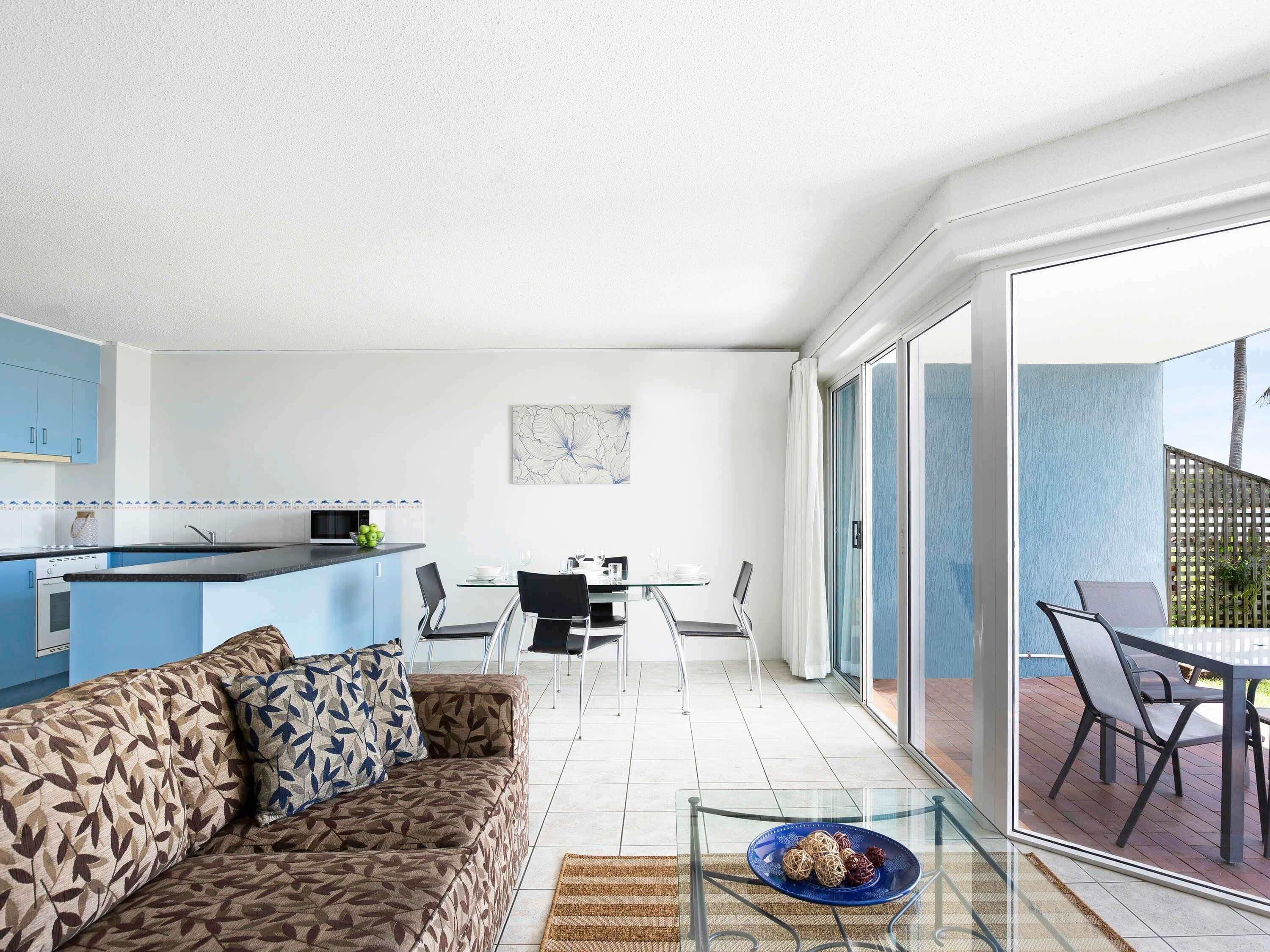 A modern living space with a sofa, dining table, and kitchen area.