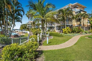 Un resort con piscina, palmeras y un césped bien cuidado.