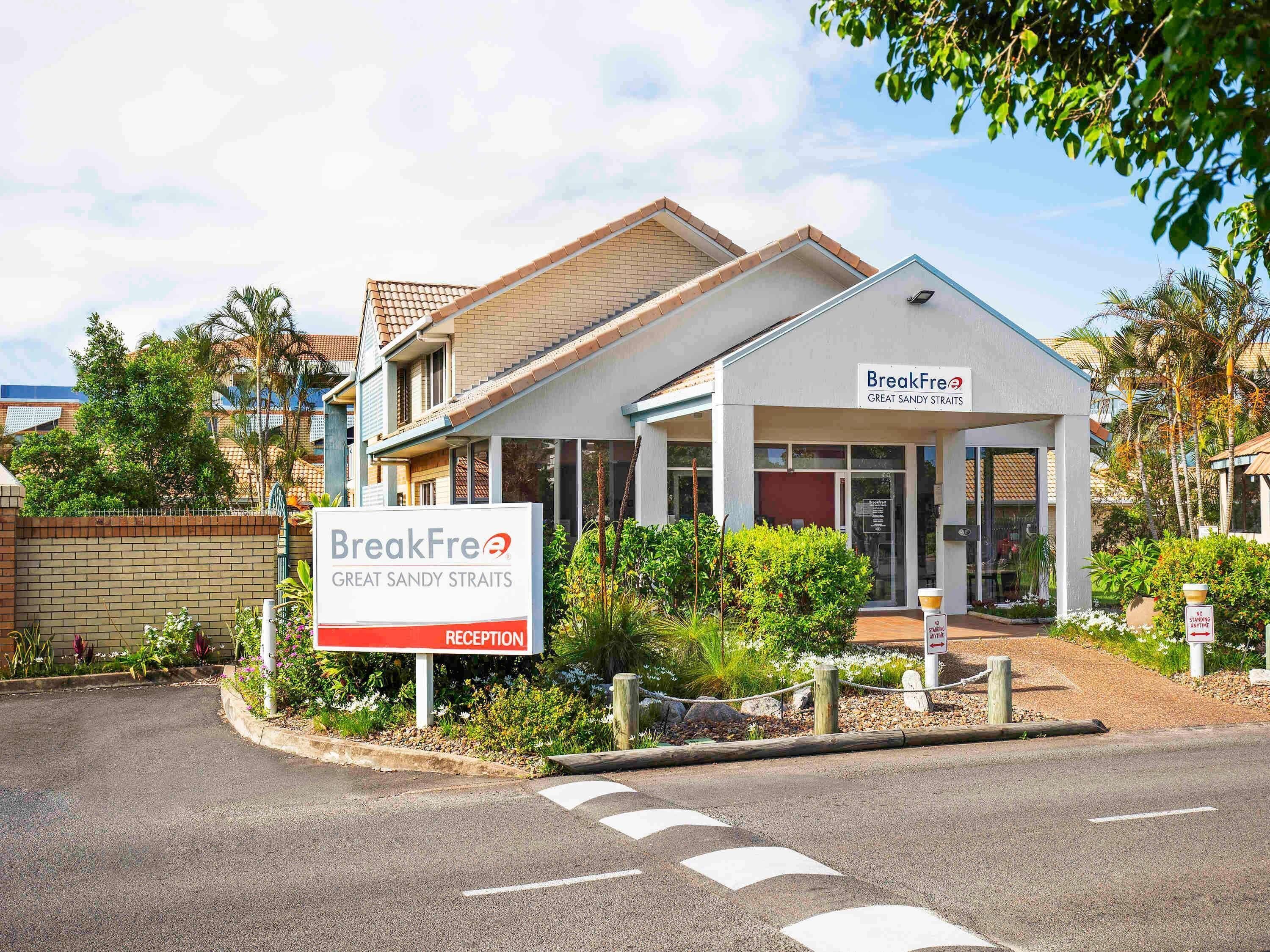 A building with a reception sign, a sign for 'BreakFree Great Sandy Straits,' and a 'No Standing Anytime' sign.