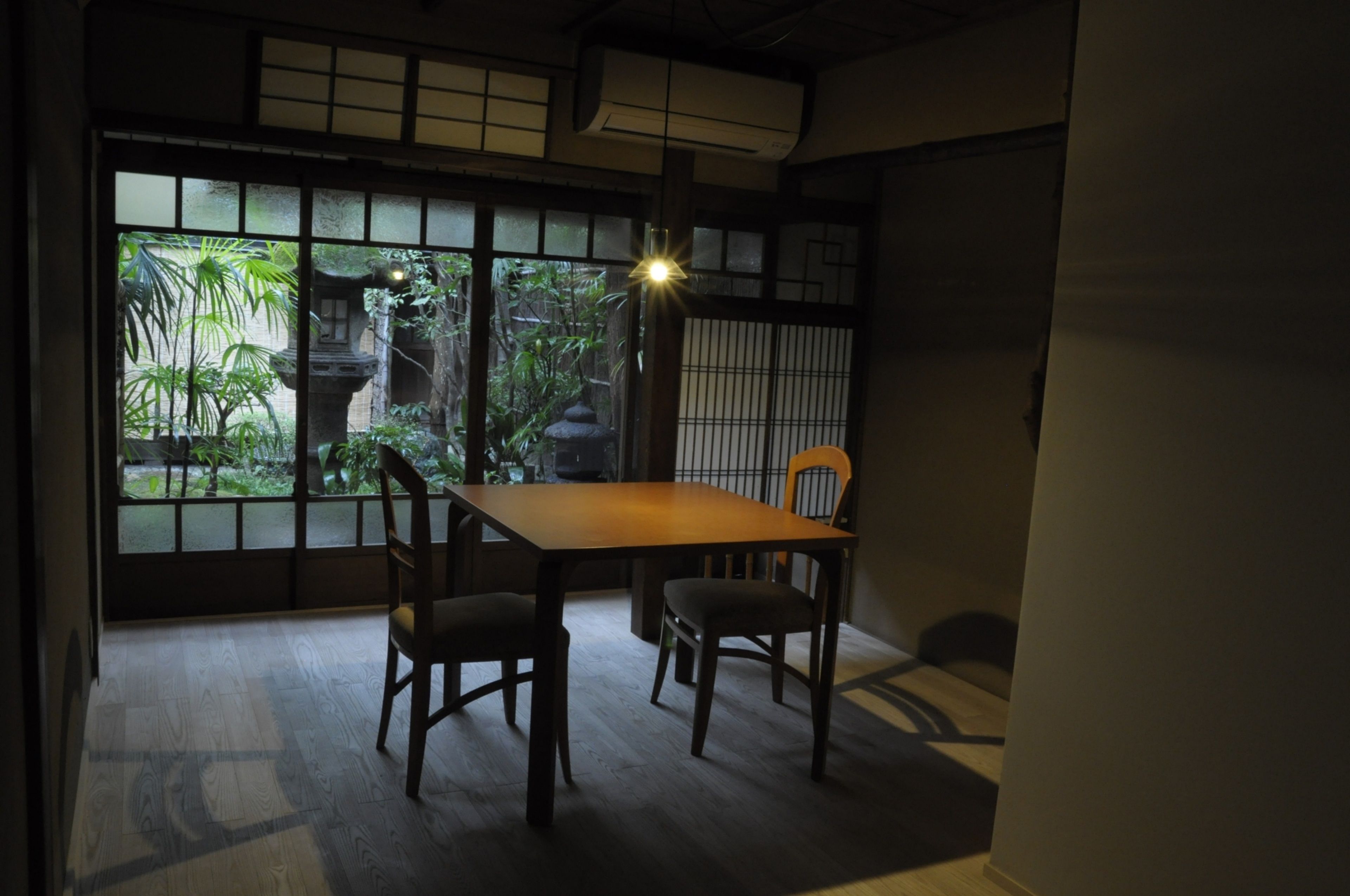 Ein traditioneller japanischer Raum mit Tatami-Bodenbelag, einem niedrigen Tisch und einer Schiebetür zu einem Garten.