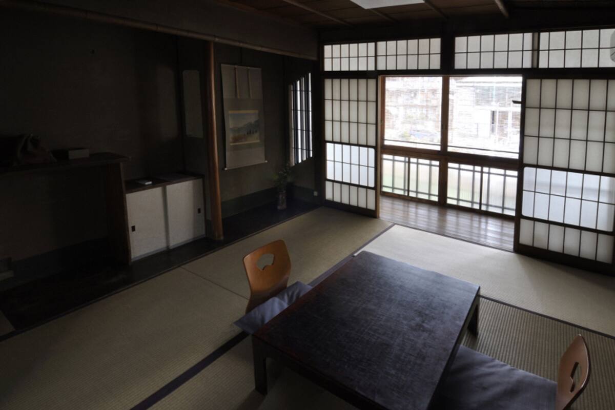 A traditional Japanese room with tatami flooring, a low table, and sliding doors.