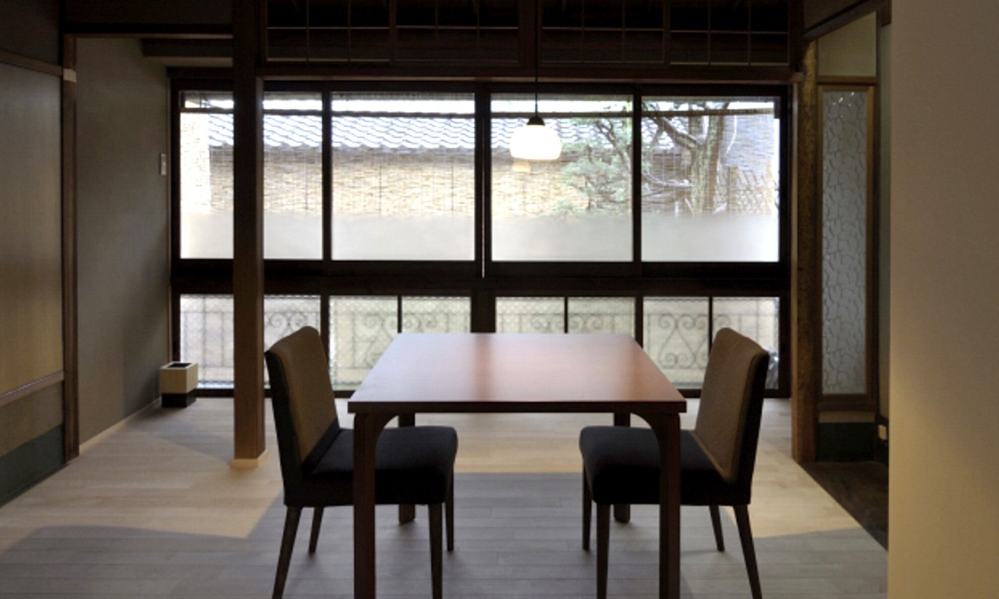 Una habitación con un ventanal grande, una mesa de madera y cuatro sillas.
