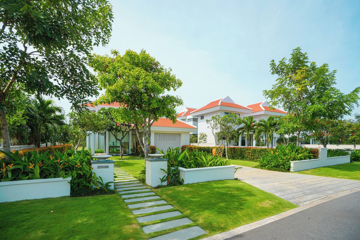 A modern residential area with well-maintained lawns, a stone pathway, and houses with red roofs.