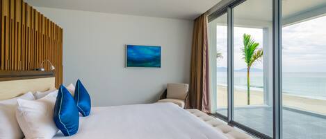 Habitación de hotel con una cama grande, vista al océano y un panel de pared de madera.