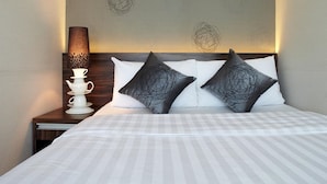 A neatly made bed with striped bedding, two pillows with a black and white design, a bedside table with a lamp, and a cup and saucer set. - Bridal Tea House Hung Hom Gillies Avenue South (Kowloon)