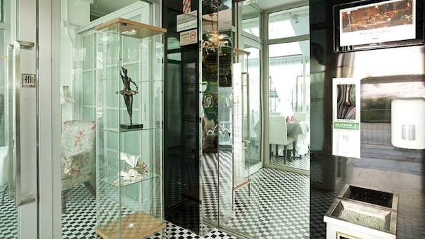 A room with a glass display case containing various items, a checkered floor, and a wall-mounted television. - Bridal Tea House Hung Hom Gillies Avenue South (Kowloon)