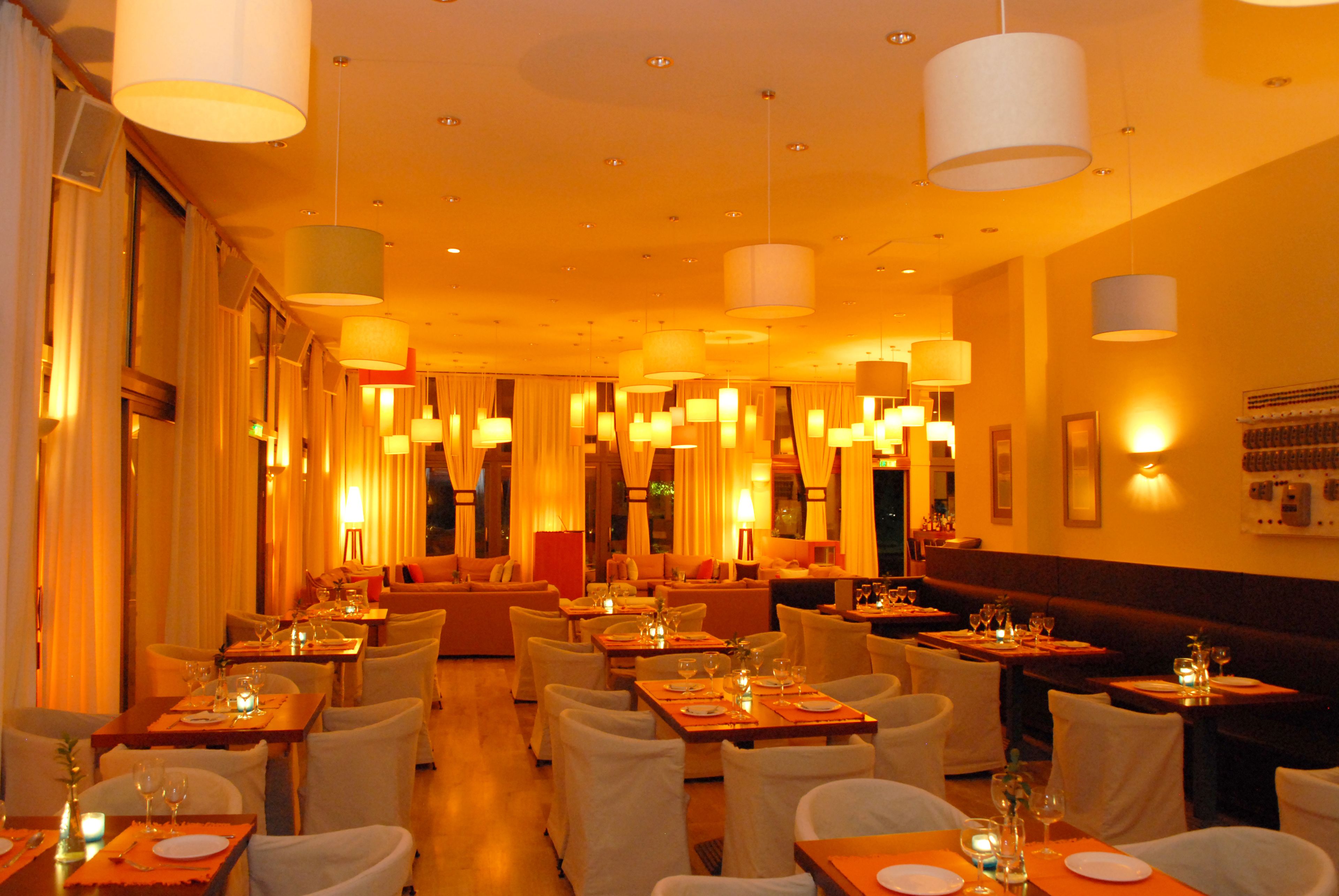 A restaurant with multiple dining tables and chairs, warm lighting, and a cozy atmosphere.