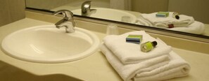 A bathroom sink with a mirror, a towel, and toiletries.