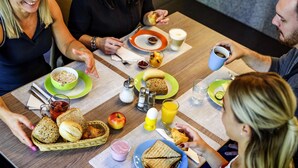 Un grupo de personas comiendo en una mesa con diversos alimentos para el desayuno, como tostadas, fruta y bebidas.