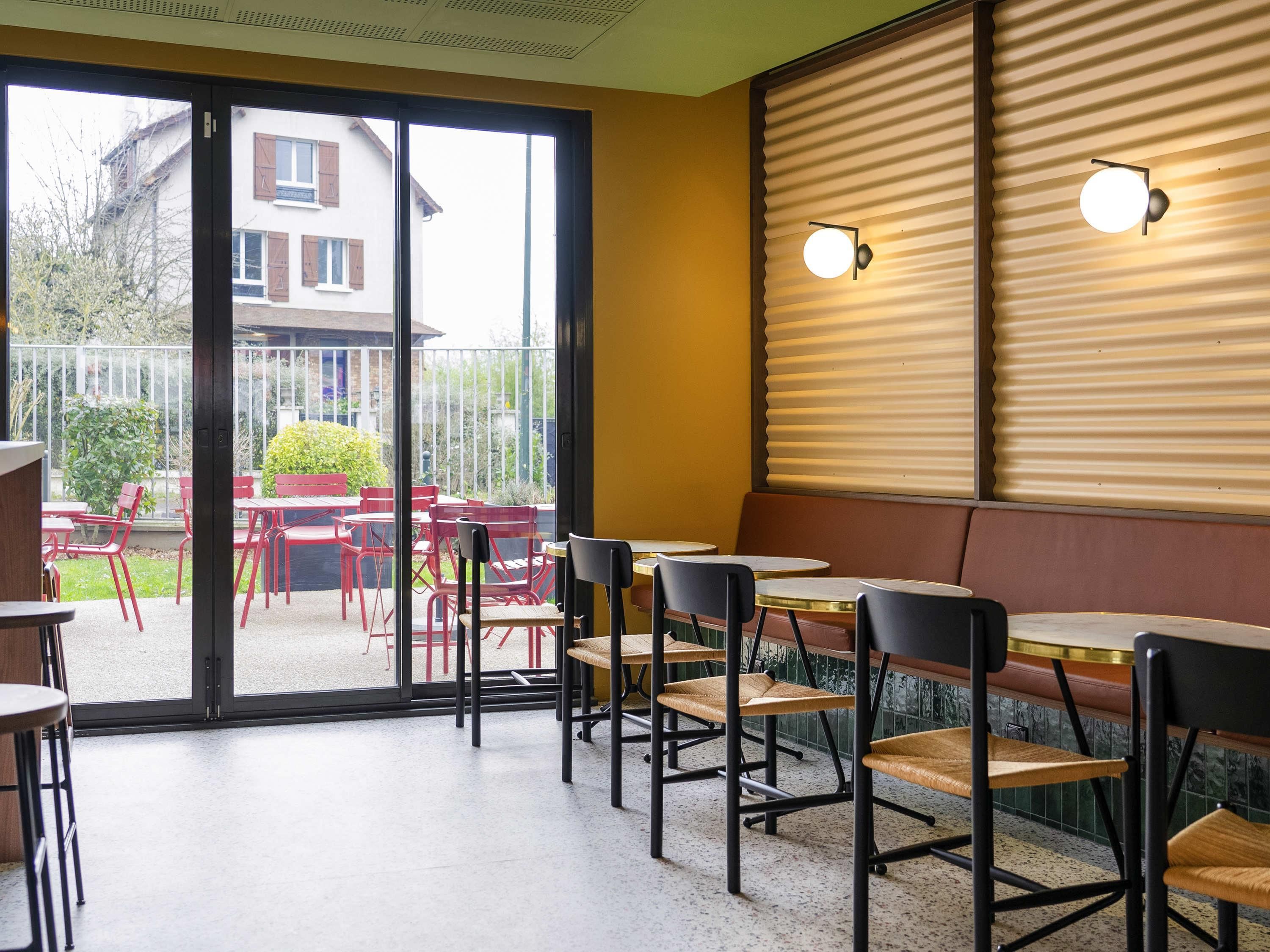 A restaurant interior with a glass door leading to an outdoor seating area, tables, and chairs.
