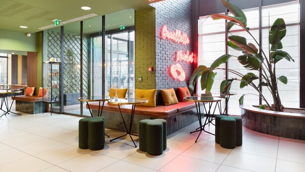 Een modern café met zitgedeeltes, een neonbord en grote ramen.