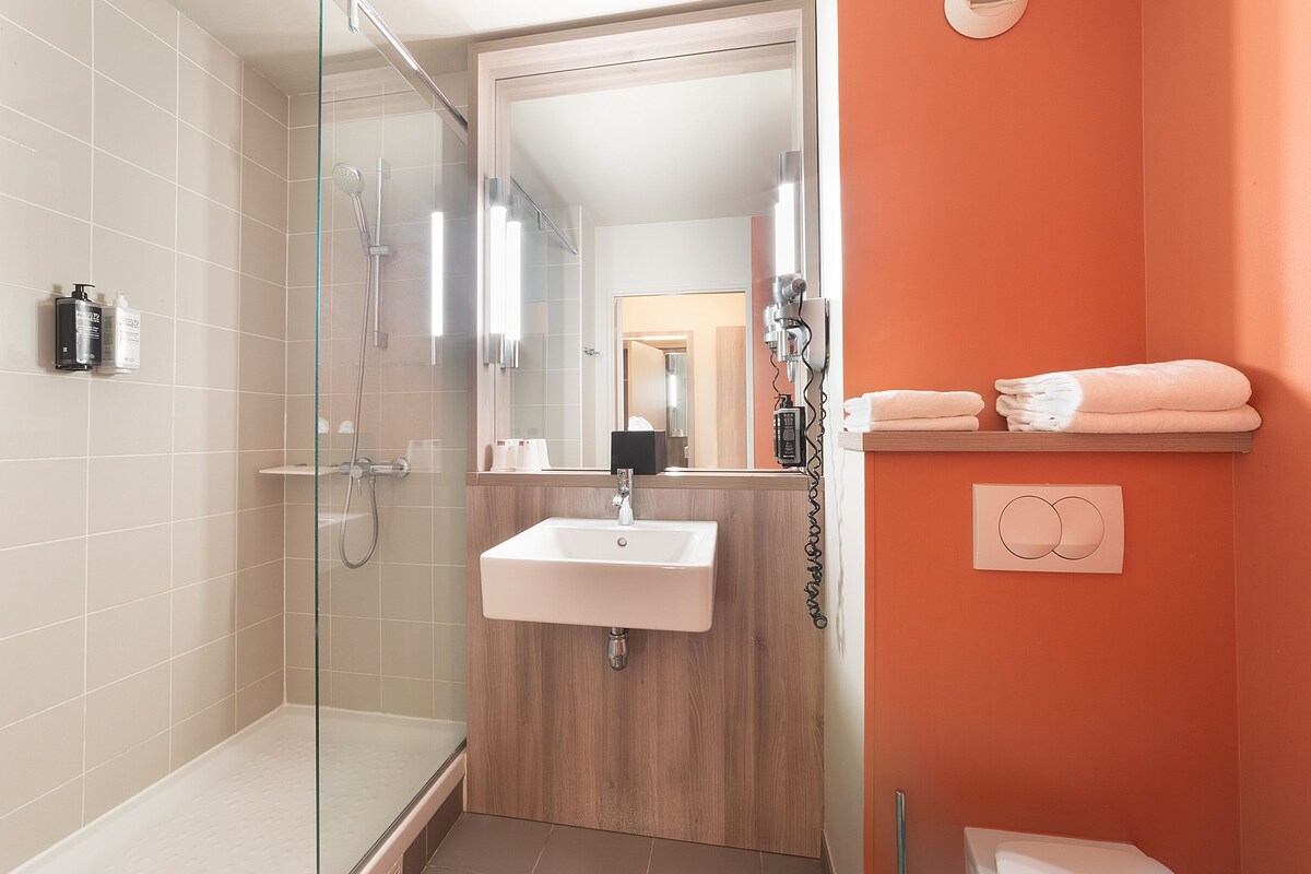 Une salle de bain avec une douche à parois de verre, un lavabo et un miroir.