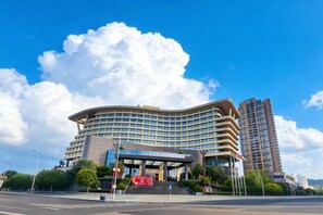 Un hotel de varios pisos con fachada curva, una entrada destacada y cielo despejado.