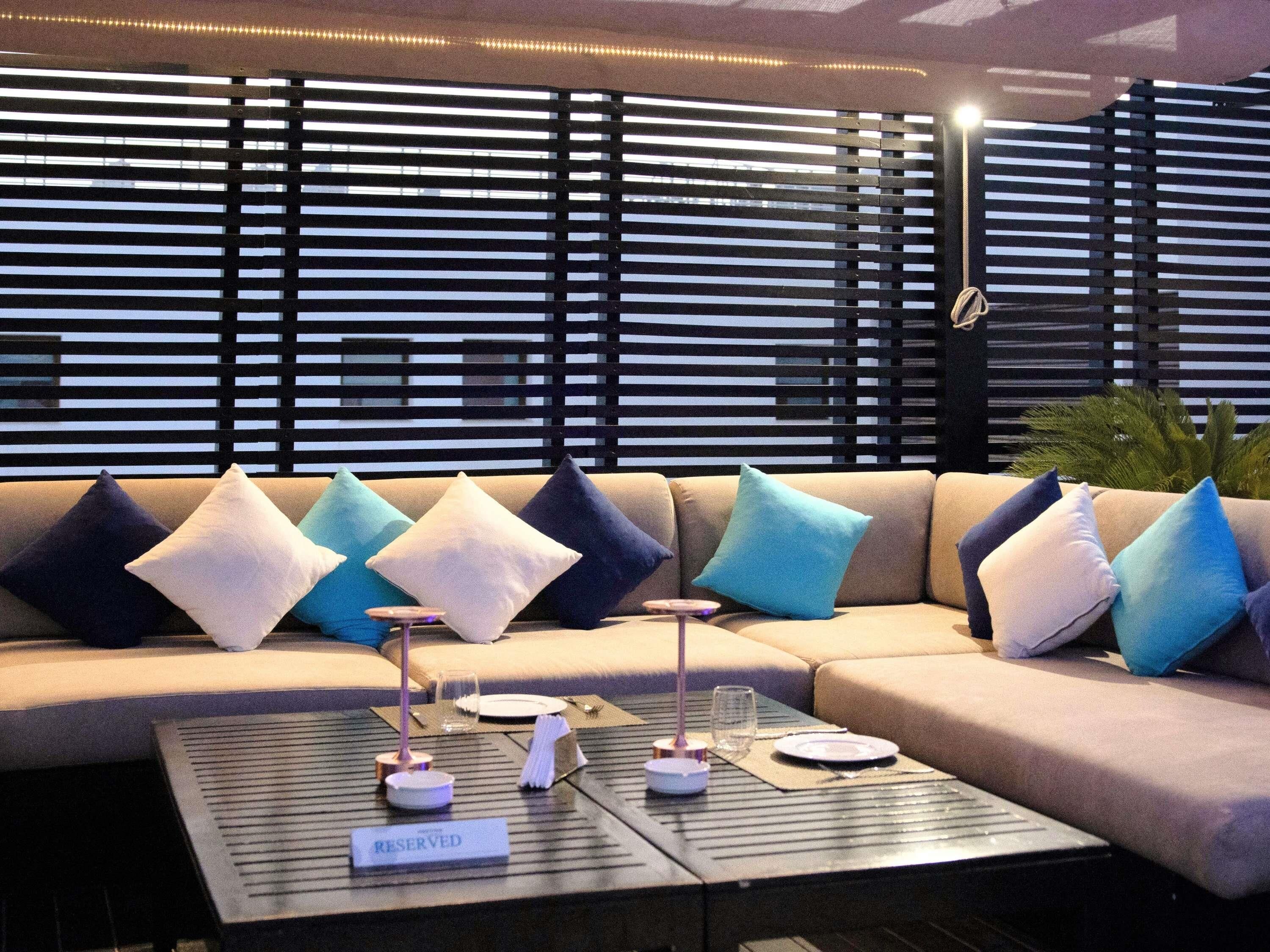 A modern lounge area with a sofa set, a coffee table with a 'RESERVED' sign, and a patterned backdrop.