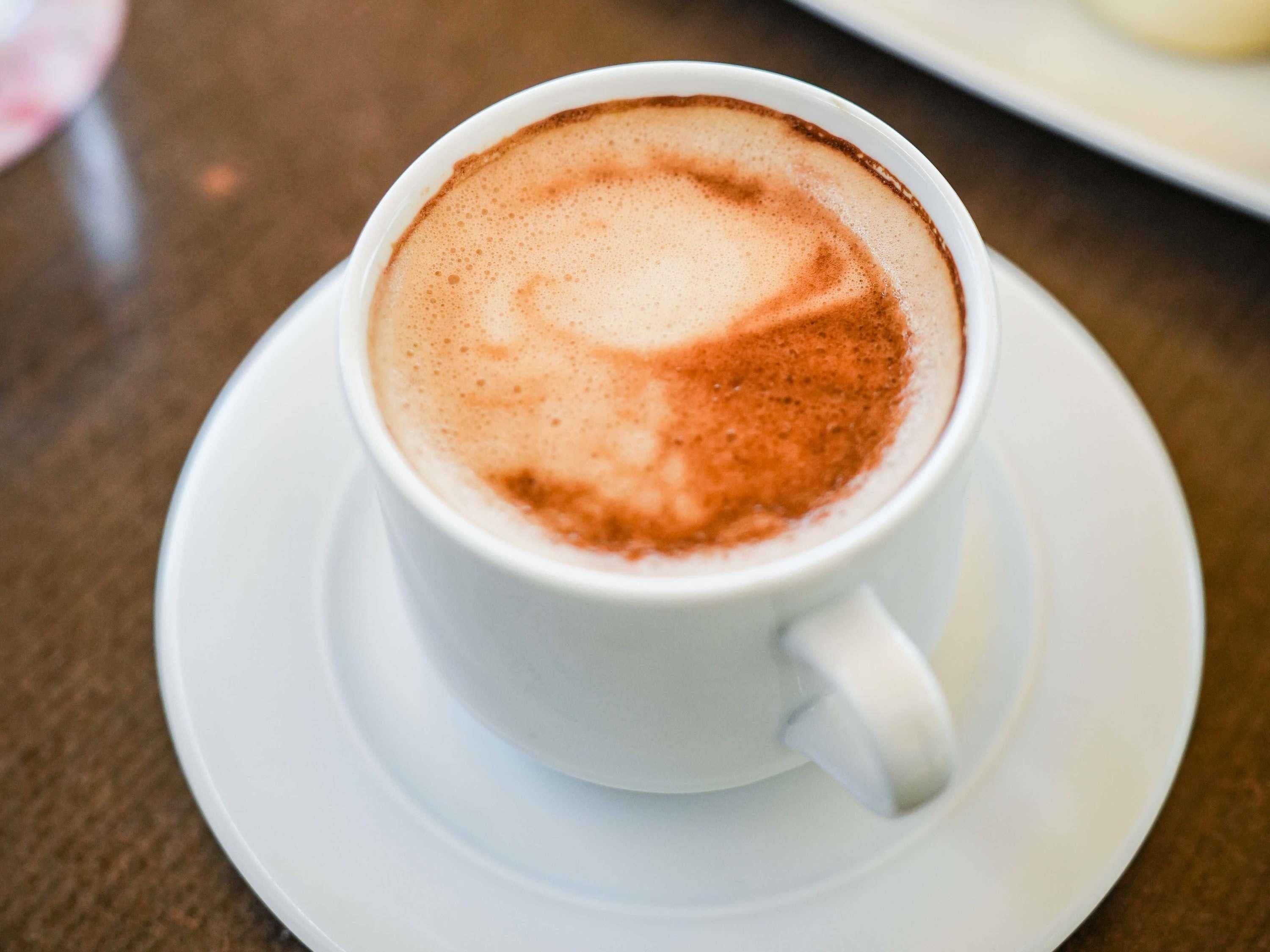 Eine weiße Kaffeetasse mit Latte-Art auf einem weißen Untertasse.
