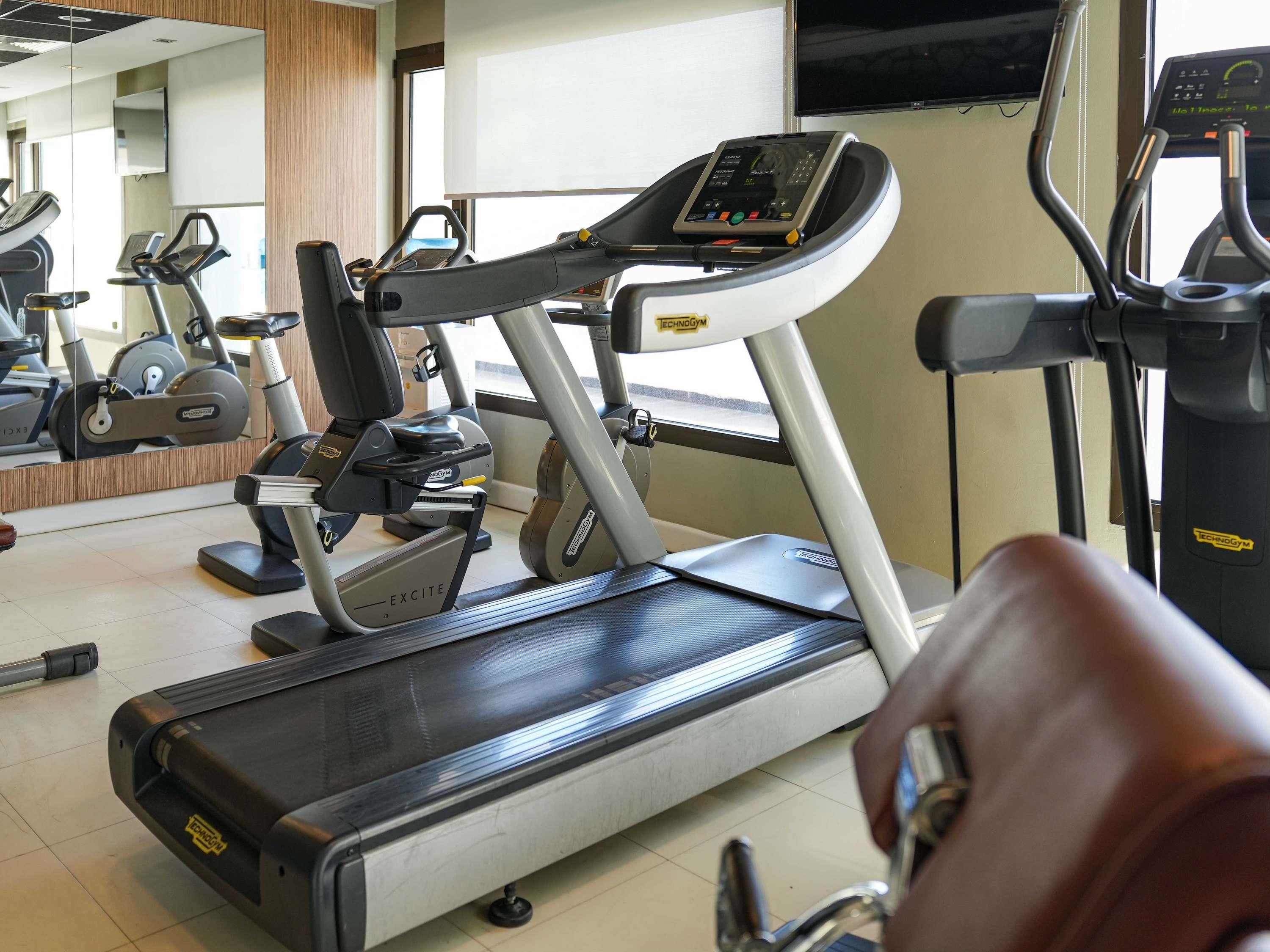 Un gimnasio con diversas máquinas de ejercicio, incluyendo cintas de correr y elípticas.