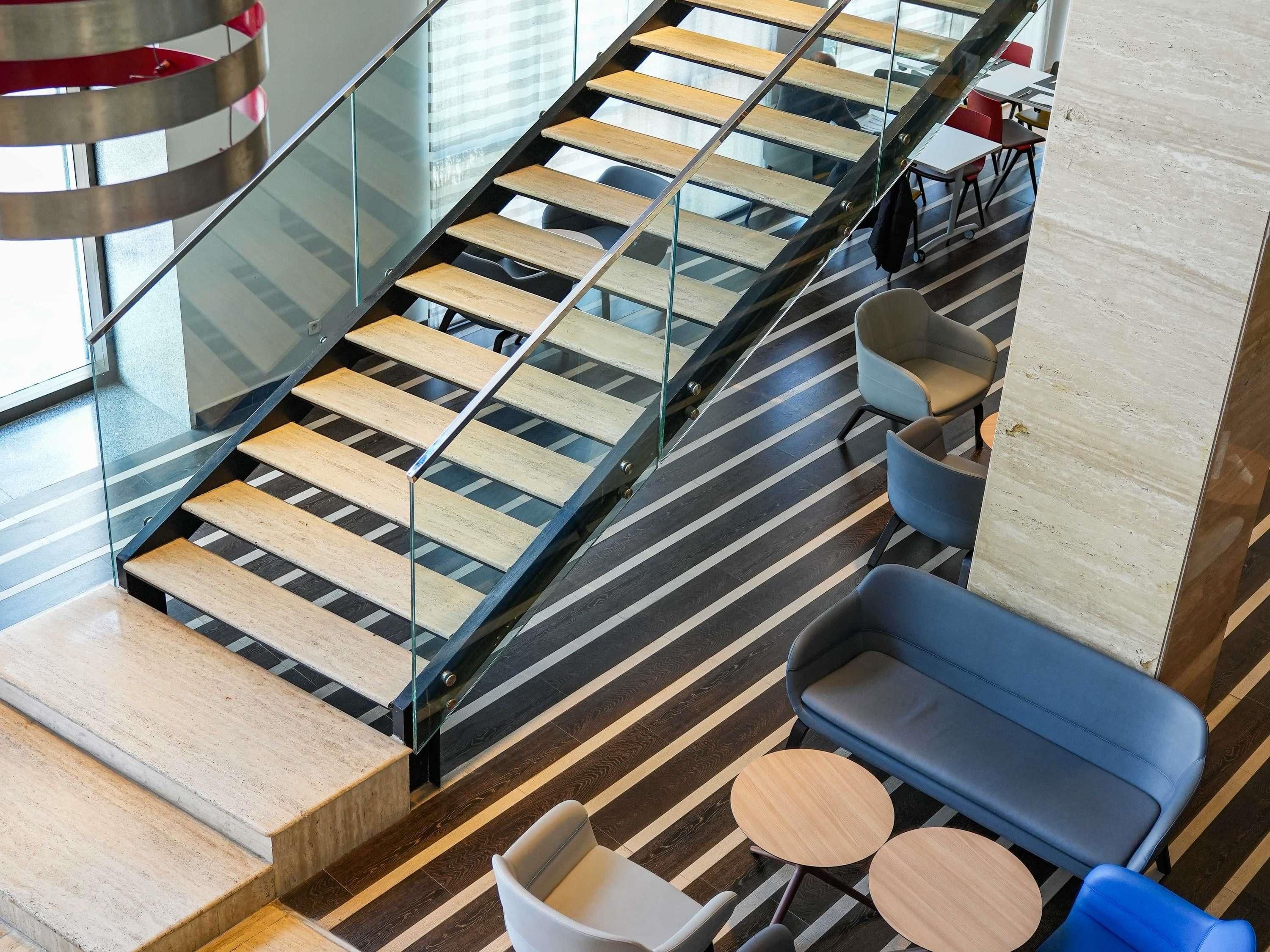 Un intérieur moderne avec un escalier en verre, des marches en bois et des espaces de détente contemporains.