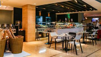 A modern restaurant with a central bar area, seating for guests, and a visible kitchen in the background.