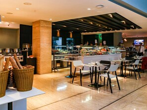 A modern restaurant with a central bar area, seating for guests, and a visible kitchen in the background.