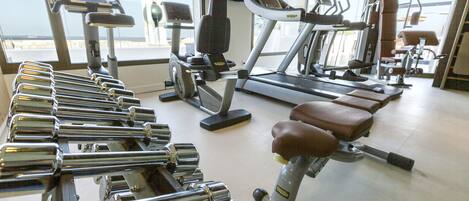 Une salle de sport équipée de divers appareils d’exercice, notamment des tapis de course, des appareils de musculation et des haltères.