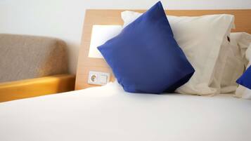 A hotel room with a bed, a wooden headboard, and a bedside table.