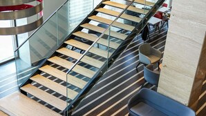 Un interior moderno con una escalera de cristal, escalones de madera y zonas de estar contemporáneas.