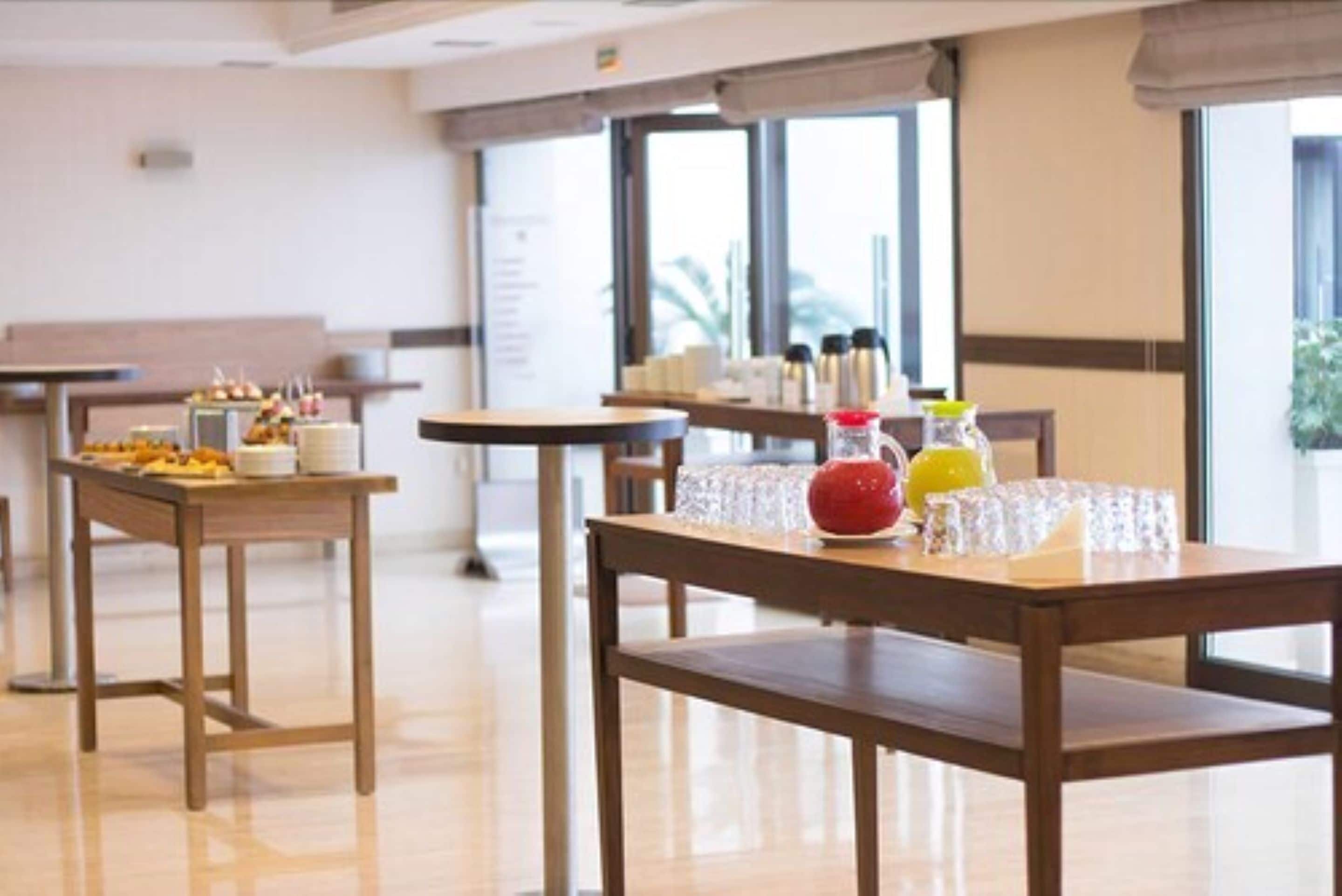 A dining area with tables set for breakfast, including fruits and beverages.
