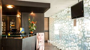 A reception area with a modern design, including a reception desk, a digital screen, and a decorative wall with a geometric pattern. - Novotel Tunis (Tunis)