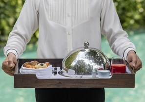 A person holding a tray with a covered food item, a glass of red drink, and a small cup. - 137 Pillars House (Chiang Mai)