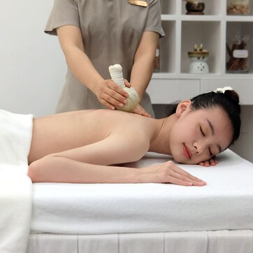 A person receiving a massage with a white towel covering their lower body.