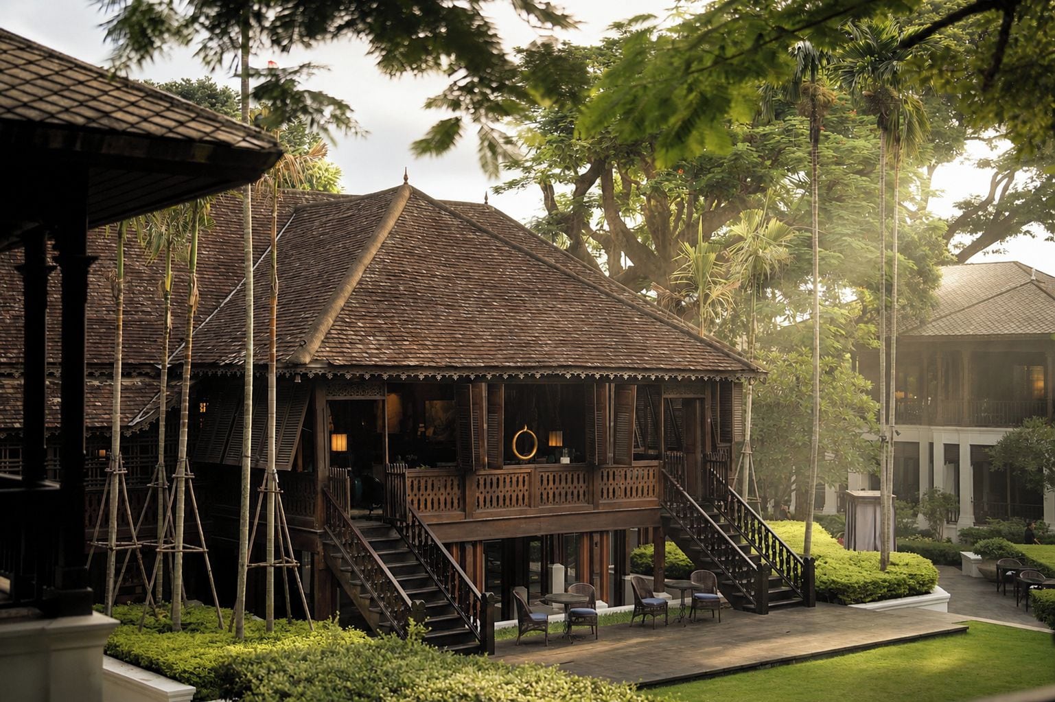 Un edificio de madera tradicional con balcón, escaleras y zona de estar al aire libre.