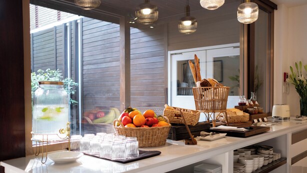 A breakfast buffet setup with wicker baskets, plates, and a variety of food items.