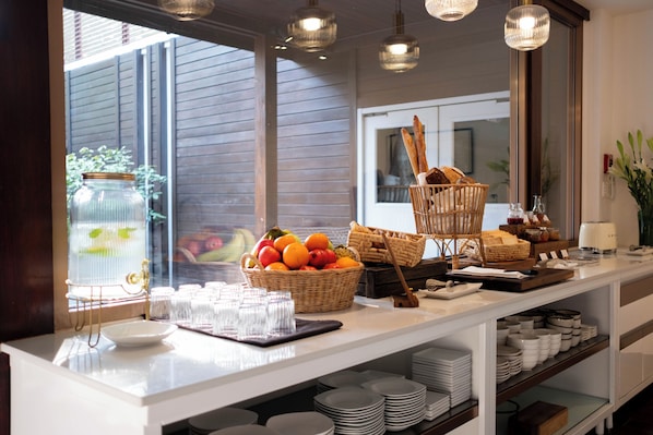 A breakfast buffet setup with wicker baskets, plates, and a variety of food items. - 137 Pillars House (Chiang Mai)