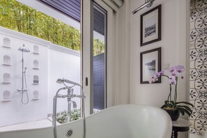 A bathroom with a bathtub, shower, and a potted orchid. - 137 Pillars House (Chiang Mai)