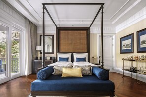 A four-poster bed with a canopy, a sofa with blue upholstery, and a bedside table with a lamp.