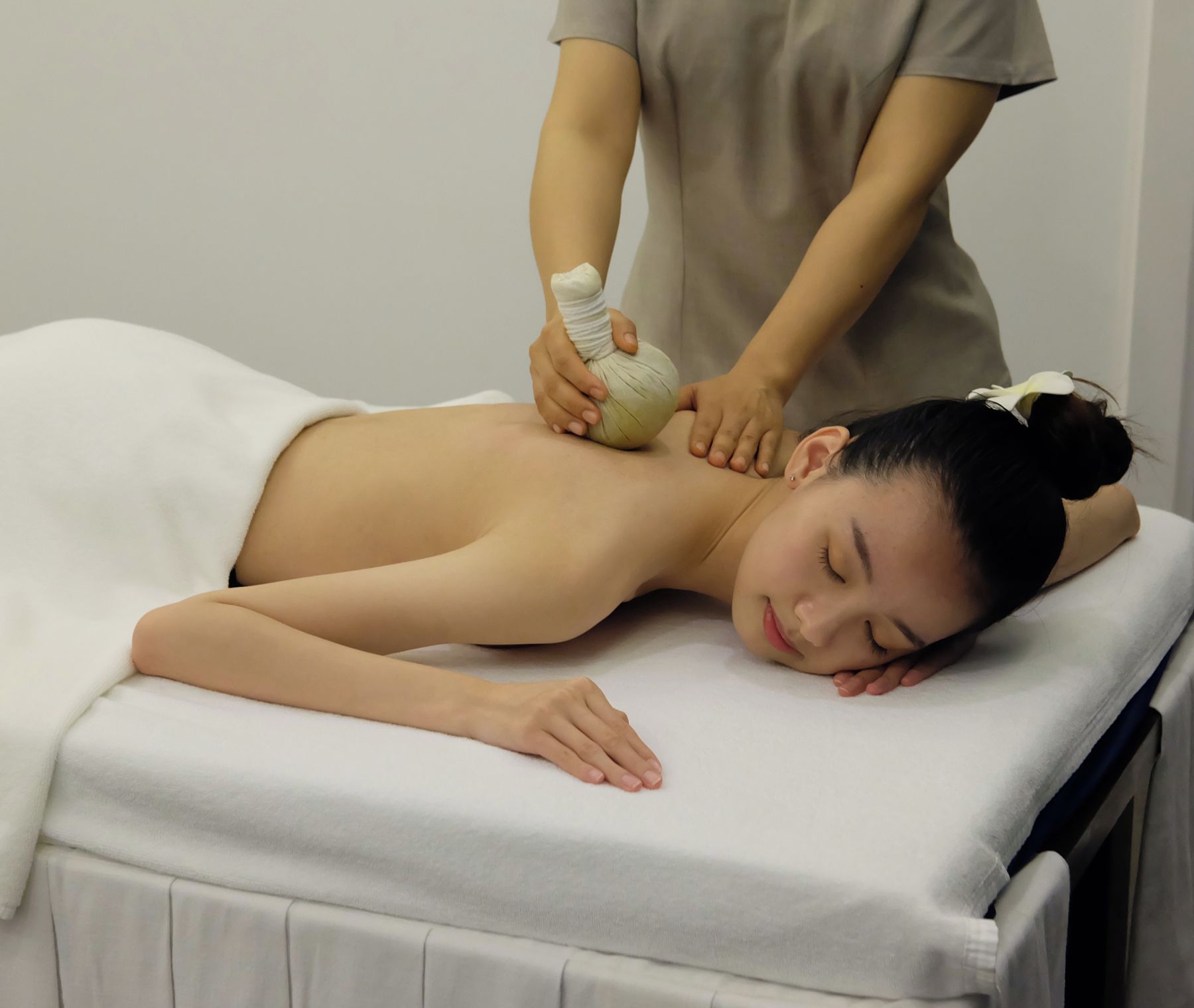 A person receiving a massage with a rolled towel on their back.
