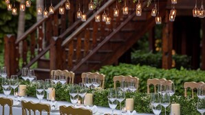 A table set with wine glasses, candles, and a wooden staircase in the background. - 137 Pillars House (Chiang Mai)