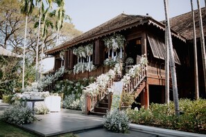A traditional wooden building with a staircase and white floral decorations. - 137 Pillars House (Chiang Mai)