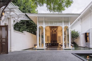 Um edifício de estilo tradicional com entrada coberta, um pátio com fonte e uma área de estar com mesas e cadeiras.