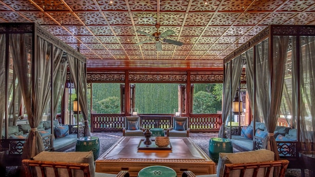 A traditional room with a wooden ceiling, a central seating area with cushions, and a view of greenery outside. - 137 Pillars House (Chiang Mai)