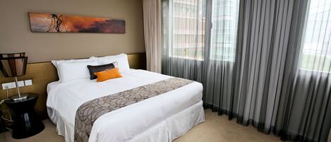 A hotel room with a large bed, a bedside table, a lamp, and a window with curtains.