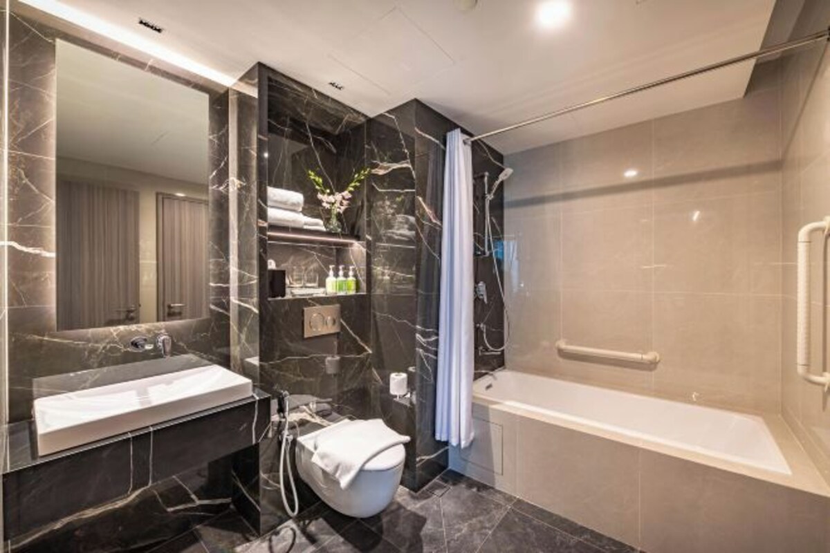 A modern bathroom with a marble vanity, a bathtub, and a shower area.