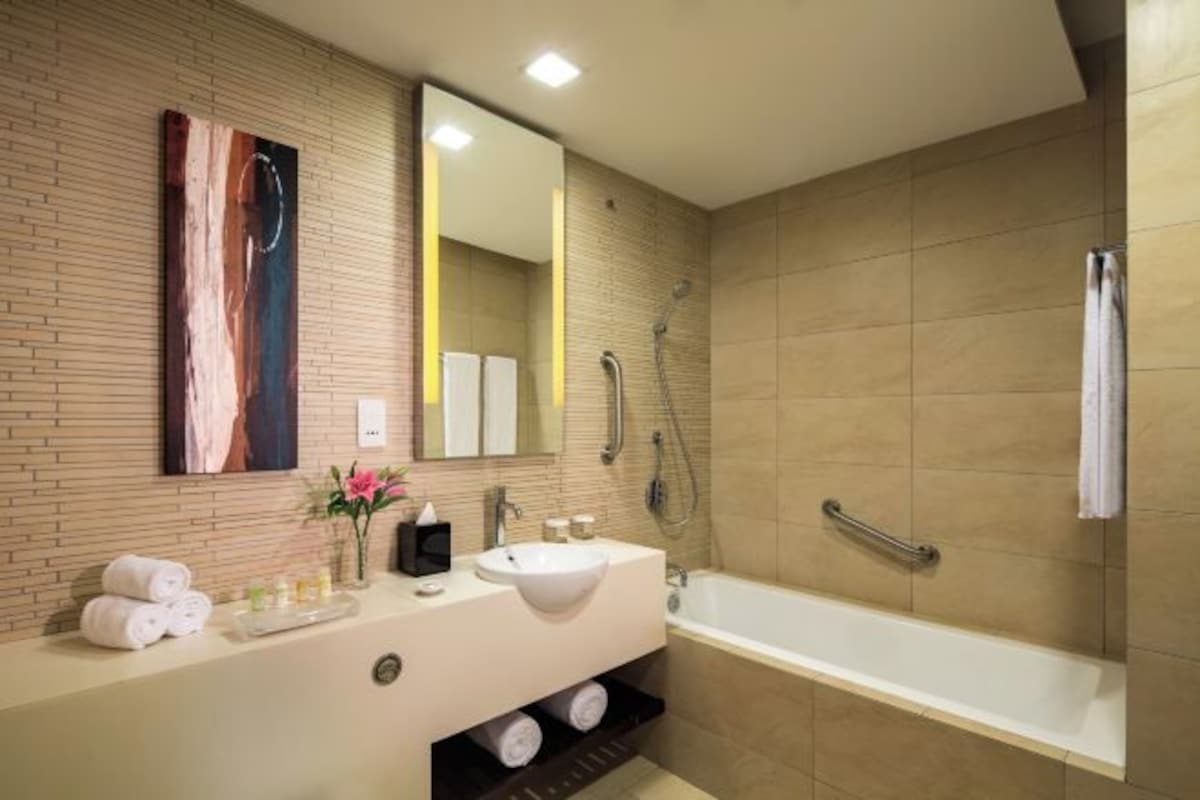 A modern bathroom with a large sink, mirror, and shower.