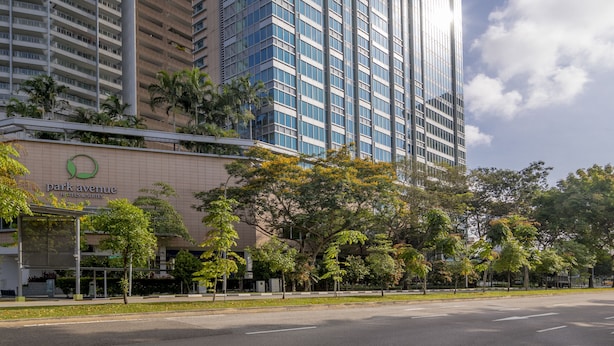 A modern hotel building with a glass facade, surrounded by trees and a clear sky. - Park Avenue Rochester (Singapore)