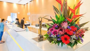 A reception desk with a floral arrangement, a statue, and a counter with a person standing behind it. - Park Avenue Rochester (Singapore)