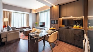A modern hotel room with a dining area, kitchenette, and a sofa. - Park Avenue Rochester (Singapore)