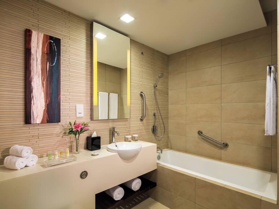 Un bagno moderno con un lavandino capiente, uno specchio e una doccia.